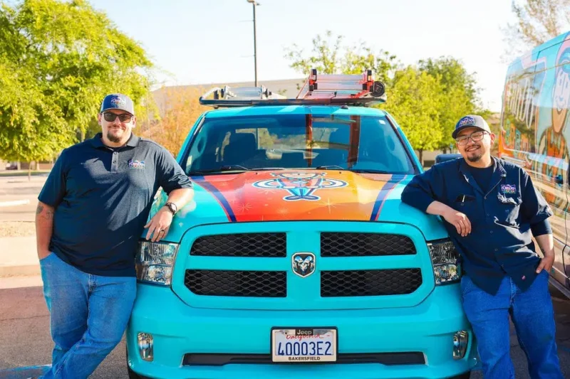 HVAC service team standing next to branded company vehicle