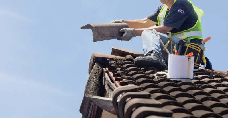 Technician performing roofing repairs on a residential property