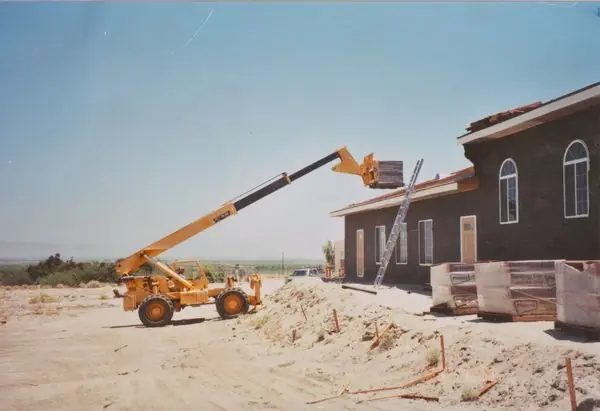 Crane lifting roofing materials onto a residential roof during construction